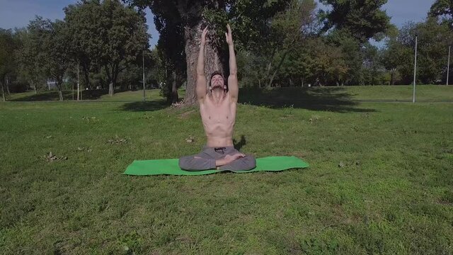 Young caucasian man practice morning yoga and stretching in the park