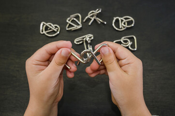 metal puzzle in hands. Black background. Close-up. Concept to solve the puzzle.