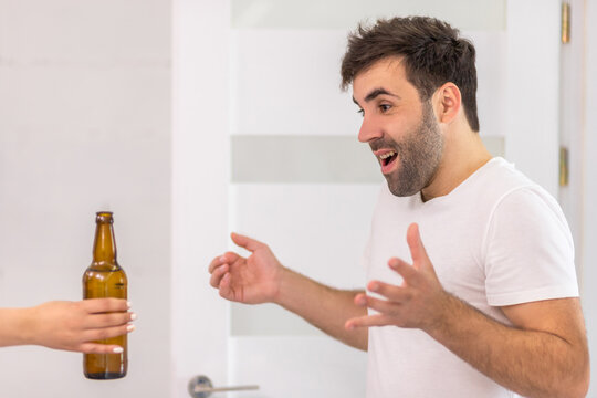 Close up photo of man looking at bottle of beer.