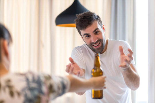 Photo of young bearded man being excited because his friend brought him a bottle of beer.