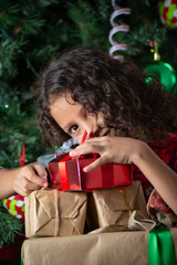 little girl with curly hair hugging Christmas present