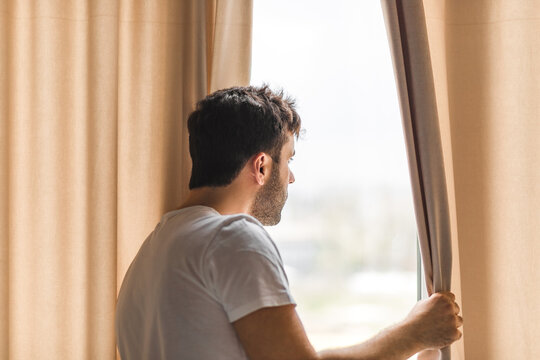 Photo of middle age bearded man looking in the window in the morning.