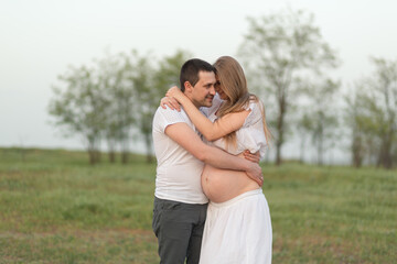 Happy moments of pregnancy. A loving husband with his pregnant wife in the fresh air away from the city