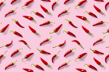 Creative background made of red chili or chilli on pink backdrop. Minimal food backgroud. Red hot chilli peppers background.