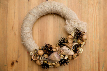 The natural wreath is adorned with pine cones, nuts, seeds and linen threads. Festive background with an Advent wreath. Christmas lights. Handmade decoration.