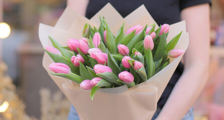 Woman holding big beautiful blossoming mono bouquet of fresh pink tulips flowers. Fresh pink tulips bouquet. Beautiful flowers