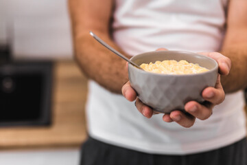 Photo of bowl of corn flakes with milk and spoon inside isolated on blurred background.