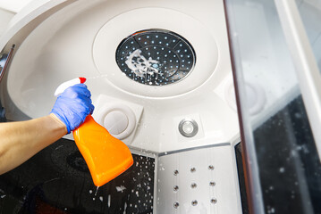 Cleaning of shower steam cabins from calcium deposits. Cleaning in the bathroom. hand in gloves with rag and detergent washing shower and glass