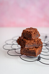 Homemade brownie on black cooling rack with pink background 