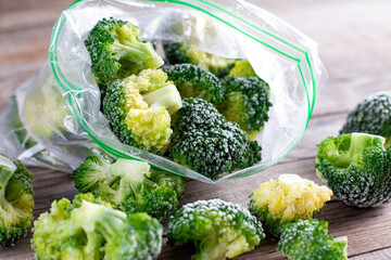 Frozen broccoli in a plastic bag on wooden table. Selective focus.