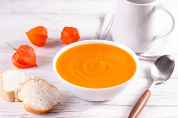Pumpkin and carrot soup on a white plate. Vegetarian food concept.