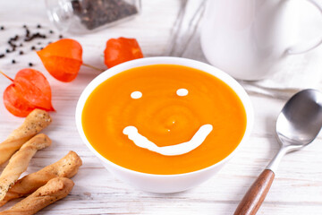 Funny food. Pumpkin puree soup with a smile as decoration, top view. The concept of baby food.