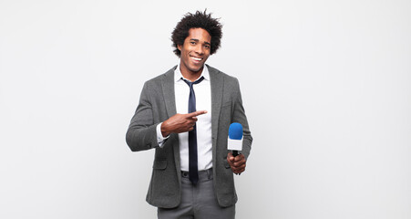 young black afro man looking excited and surprised pointing to the side and upwards to copy space