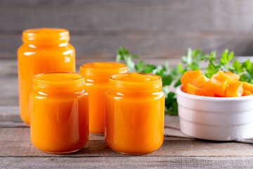 Homemade baby pumpkin puree in glass jars and fresh pumpkins on white background. The concept of baby food.