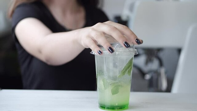 The takeaway drink preparation. The cold mochito is prepared by a barista in cafe.