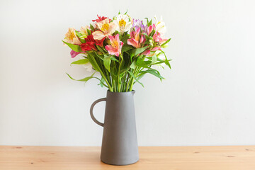 Colorful flowers in a cement vase on a wooden table