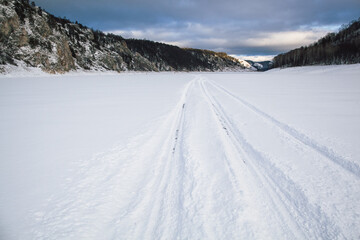 Fototapeta na wymiar tire tracks in the snow, winter road, empty road in winter goes far to the horizon, covered with snow path, winter landscape