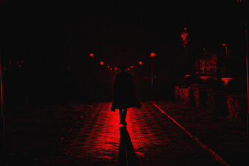 dark silhouette of a male detective in a coat and hat in the rain