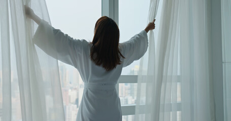 Woman open curtain at morning