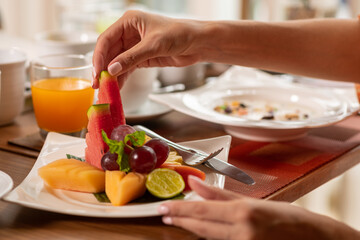 Obraz na płótnie Canvas Close-up: a woman takes watermelon from a fruit plate. Healthy breakfast