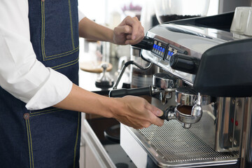 Hand of barista man holding coffee tamper with grind coffee for making coffee for customers