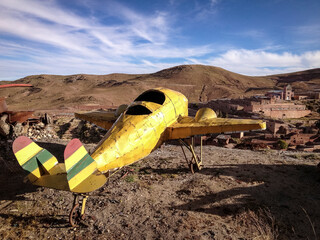 Old two-seater, yellow fair airplane placed in a mountain near a junkyard, in the town of Pulacayo,...