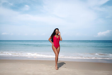 Fototapeta na wymiar Beautiful asian woman in red swimsuit relaxing on beach during summer vacation travel