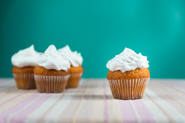 Muffin with white cream on top on a turquoise background