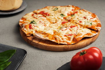 Pizza with cheese and vegetables near tomatoes and greens