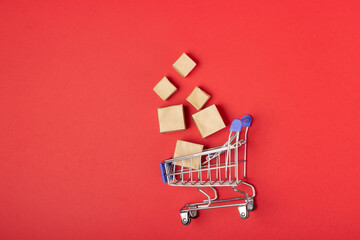 Shopping basket and boxes with purchases with place to add text on a red background. Online shopping and sale concept