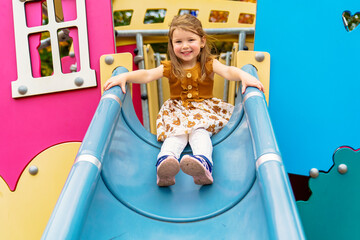 Happy Smiling Child Girl Playing At Playground Outdoors In a nice Park on a slide