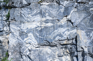 Rock cut raw surface of white and grey marble in the natural environment. Blue marble career texture. Real stone, industrial material for buildings and interior. Abstract background pattern