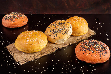 
Spiced garlic beet burger buns with poir seeds on top on black table and