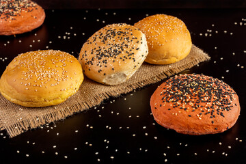 
Spiced garlic beet burger buns with poir seeds on top on black table and