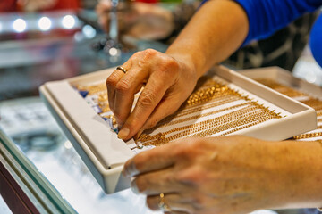 goldsmith woman hands choosing gold chain