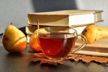 Cup of hot tea and autumn leaves and fruits on wooden background. books, berries,pears.depression,melancholia