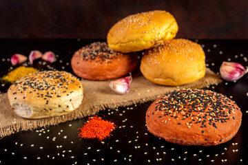 
Spiced garlic beet burger buns with poir seeds on top on black table and