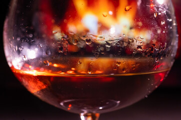 Close-up on a glass of brandy in the dark on the background of the fireplace.