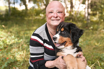 Bernese Mountain Dog puppy with his owner standing in forest park