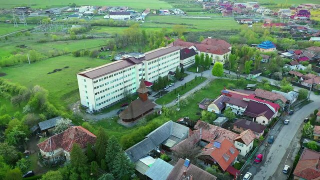 Huedin,Cluj/Romania-04.30.2020-Huedin city hospital-(Spitalul orasenesc Huedin) aerial photo, view from above. Gypsy houses in background.