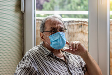 Face of elderly man wearing medical face mask, health safety concept. Aged pensioner man with gray hair wearing medical face mask looking away. Retired old man in protective face mask. Copy space.