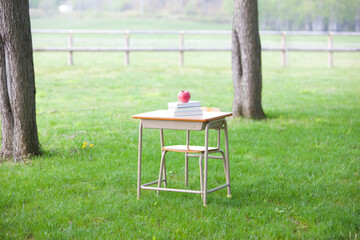 Naklejka premium 学校机に置かれた本とリンゴ