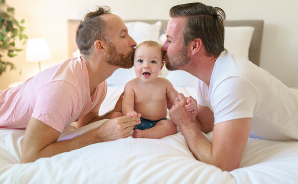 Male gay parents relaxing in bed with baby