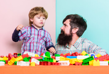 Dad and kid build plastic blocks. Child care development. Family leisure. Father and son create constructions. Bearded man and son play together. Surefire ways to bond with your son. Father son game
