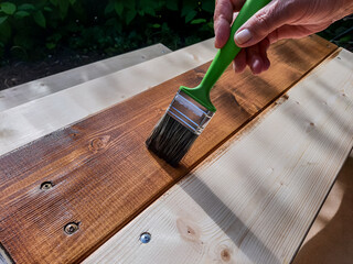 Applying protective varnish on a patio wooden floor.Painting woodwork outside.hand use brush paint...