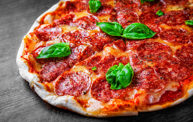Pepperoni Pizza with Mozzarella cheese, salami, Tomato sauce, pepper, Spices and Fresh basil. Italian pizza on wooden table background