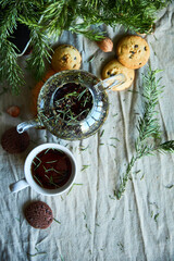 Gingerbread cookies, fruit tea and fir tree branches on a wooden black background. Christmas and New Year treat.