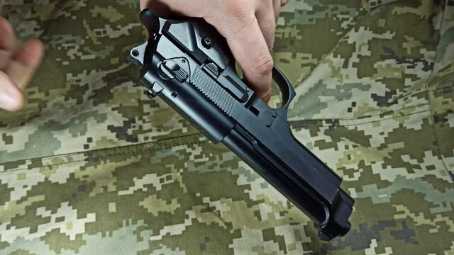 Pistol gun reloading on the khaki jacket background.