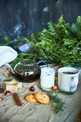 Gingerbread cookies, fruit tea and fir tree branches on a wooden black background. Christmas and New Year treat.