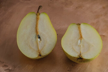The pear is cut in half on a copper surface.